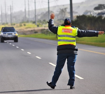 Traffic cop is seen stopping the approaching car.