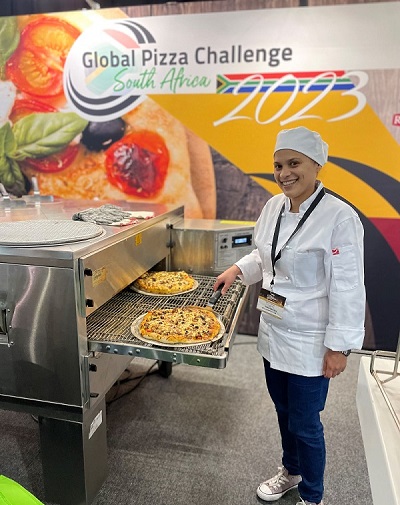 Tracy Norton is a winner of Global Pizza Challenge 2023, and she works for City Lodge Hotel V & A Waterfront in Cape Town. She is seen here with her Bobotie Pizza
