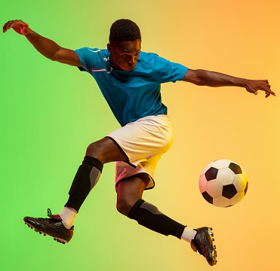 High jumping. Male soccer, football player training in action isolated on gradient studio background in neon light. Concept of motion, action, ahievements, healthy lifestyle. Youth culture